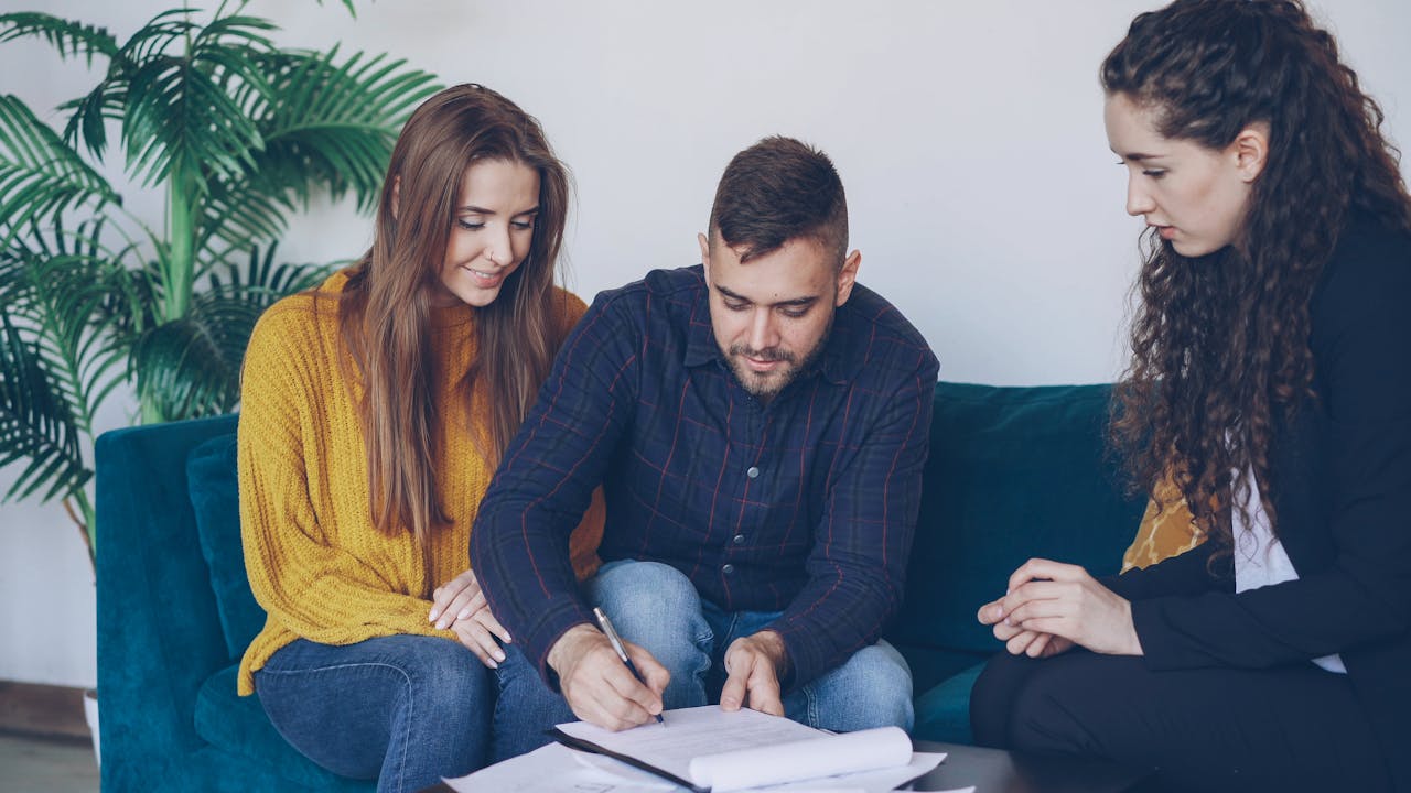 Young couple consults with financial advisor, signing important documents indoors.