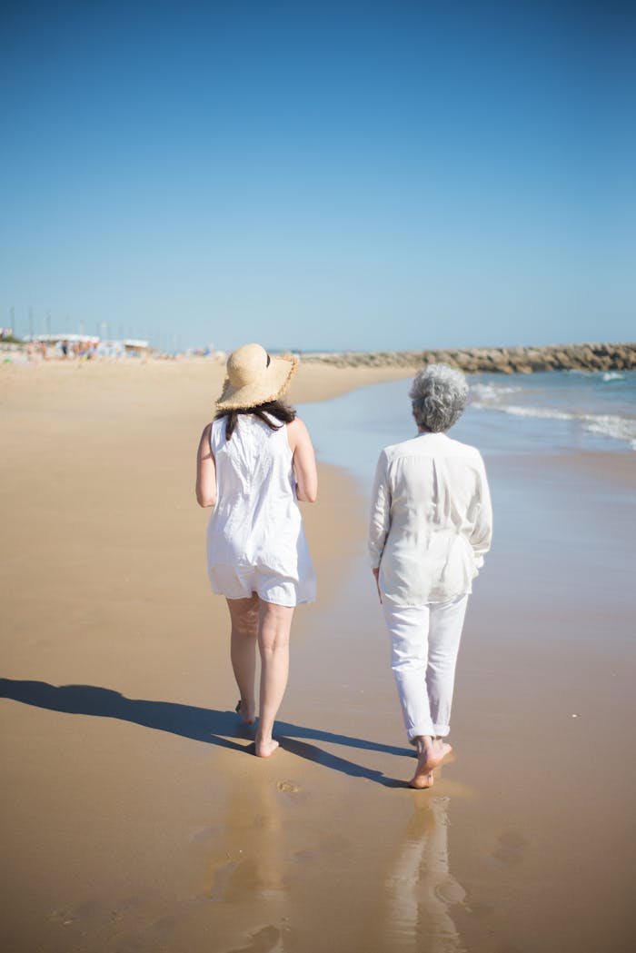 A candid moment of a mother and daughter walking together on a serene Portuguese beach.